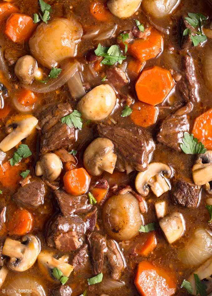 close up photo of beef bourguignon with onions, carrots, beef, mushrooms and gravy