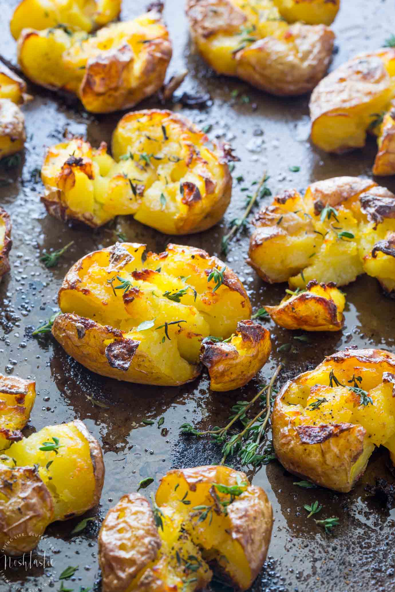 Smashed Potatoes baked with garlic, olive oil and herbs, fluffy in the middle an truly crispy in the middle, find out how to make them on noshtastic.com!! | paleo, gluten free, vegan, whole30, healthy recipe, side dish. baked potato, roasted potato.