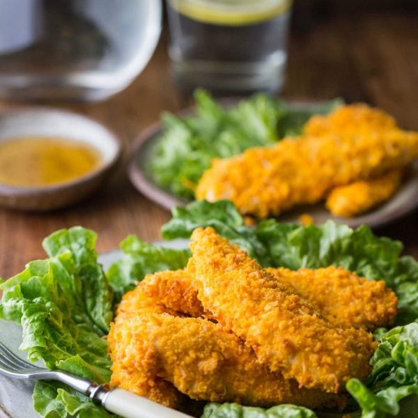 gluten free chicken tenders on a plate with glass of water