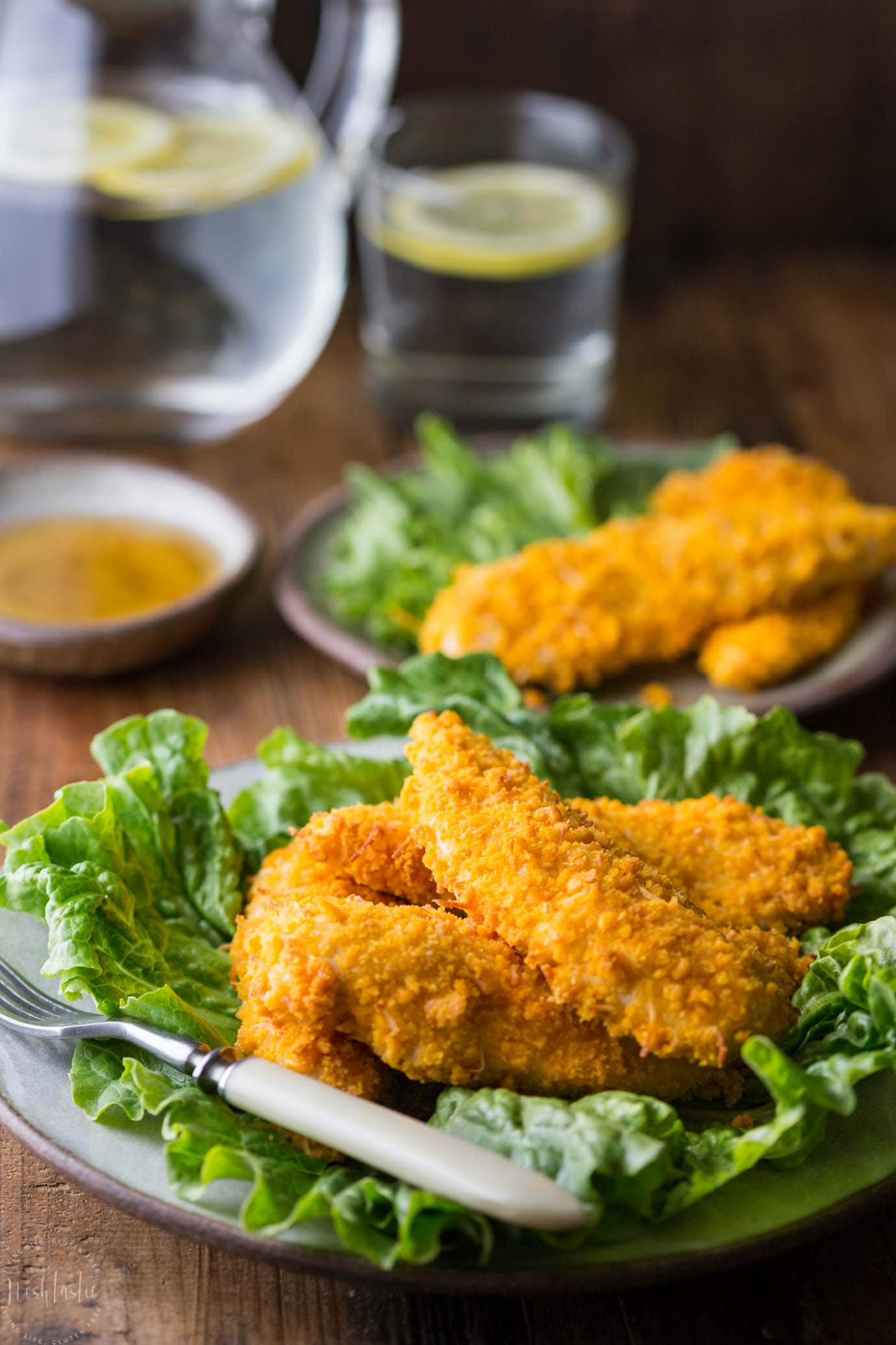 gluten free chicken tenders on a plate with glass of water