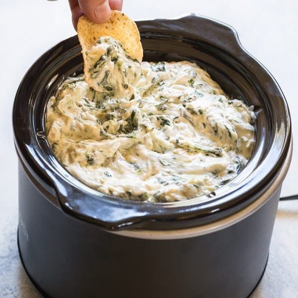 spinach and artichoke dip recipe in your crockpot or slow cooker! Made with cheese, spinach and artichoke hearts #spinachartichokedip #gameday #gamedayrecipes #chipsanddip #cheesedip #crockpotdip #partyfood #appetizer #noshtastic #glutenfree #glutenfreeappetizer