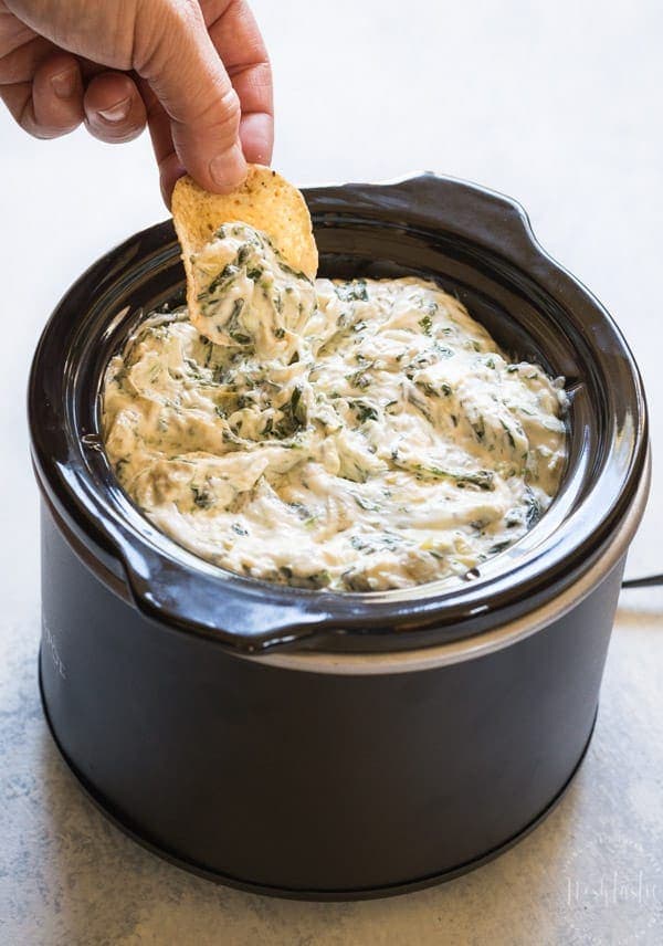 spinach and artichoke dip recipe in your crockpot or slow cooker! Made with cheese, spinach and artichoke hearts #spinachartichokedip #gameday #gamedayrecipes #chipsanddip #cheesedip #crockpotdip #partyfood #appetizer #noshtastic #glutenfree #glutenfreeappetizer