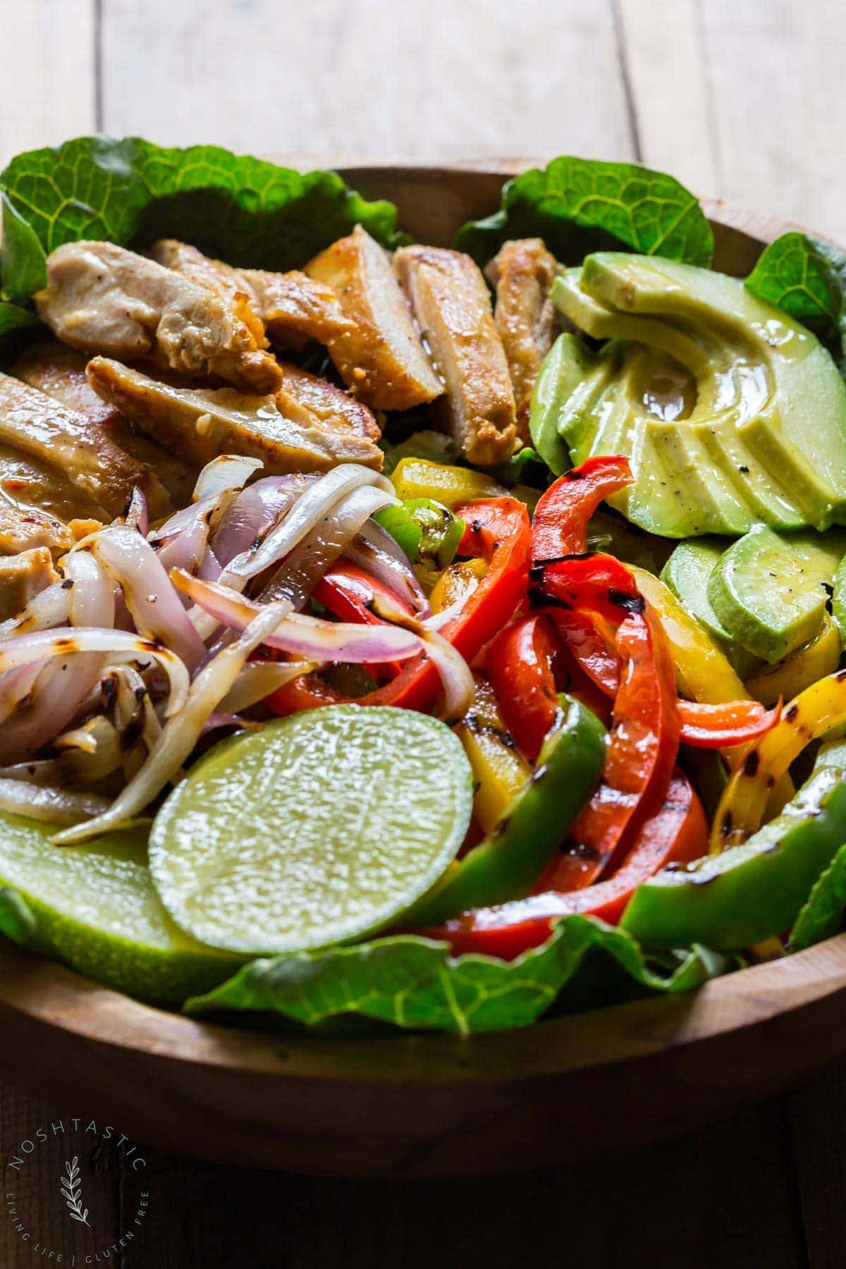 My Chicken Fajita Salad has all kinds of tasty ingredients including, grilled marinated fajita chicken, red onions, bell pepper, avocados and is topped with a fabulous honey lime salad dressing.| www.noshtastic.com | #chickenfajitas #chickenfajitasalad #fajitasalad #chickensalad #paleo #paleosalad #paleochicken #healthysalad #glutenfree #noshtastic #glutenfreerecipe 