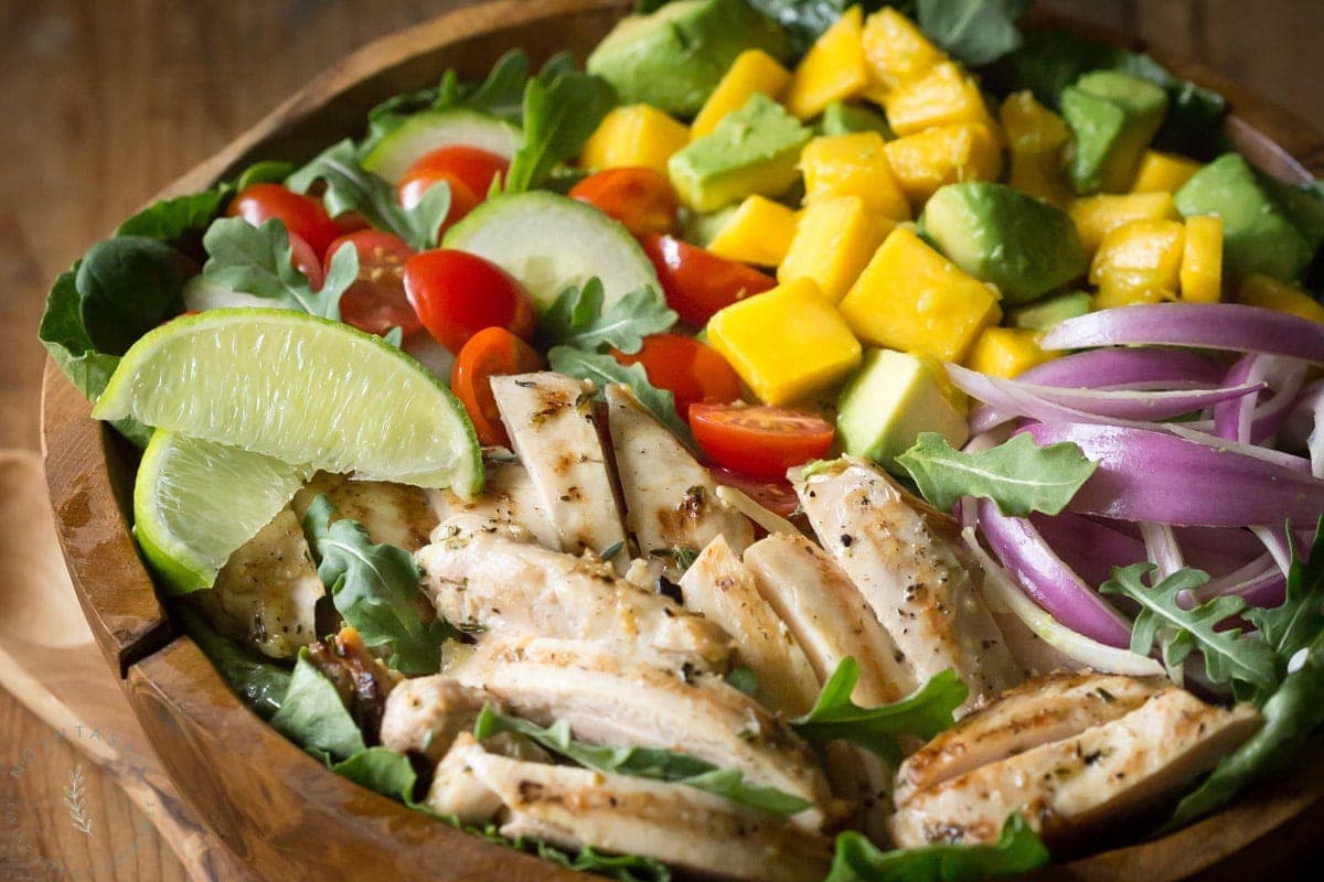 Chicken Avocado Salad with Honey Lime Dressing is such a fun summer salad! It's jam packed with healthy ingredients including arugula, spinach, and mango.| www.noshtastic.com | #chickensalad #chickenavocadosalad #glutenfreesalad #paleo #paleosalad #paleochicken #healthysalad #glutenfree #noshtastic #glutenfreerecipe 