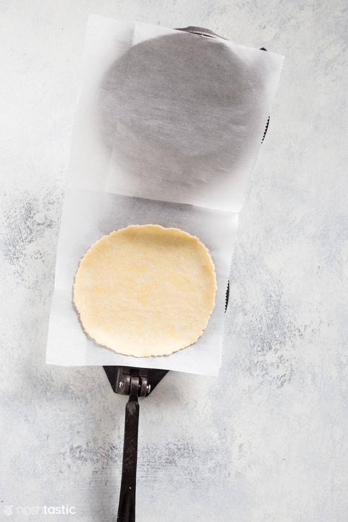 flattened tortilla in a press