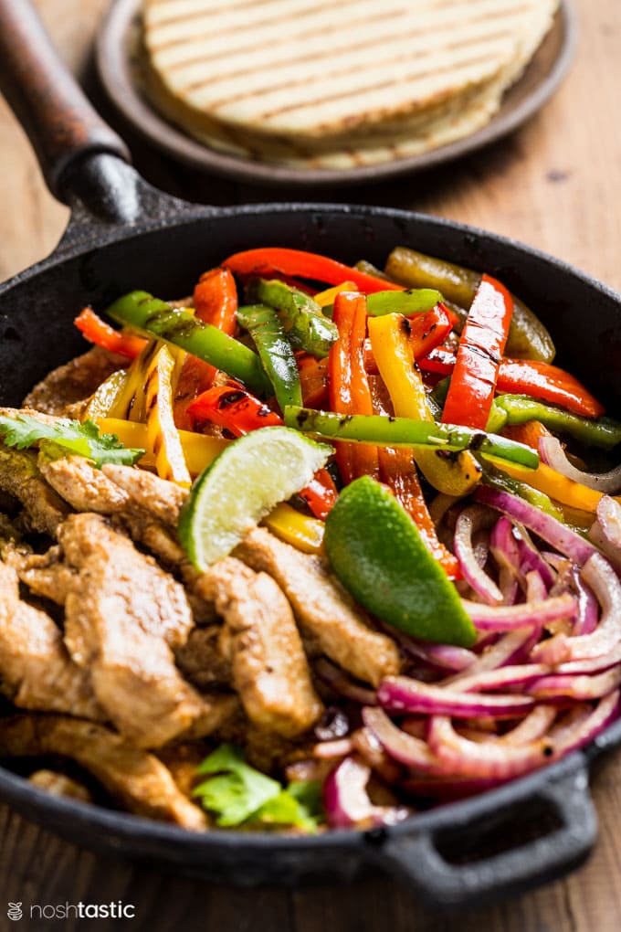 Low Carb Chicken Fajitas in a skillet with limes