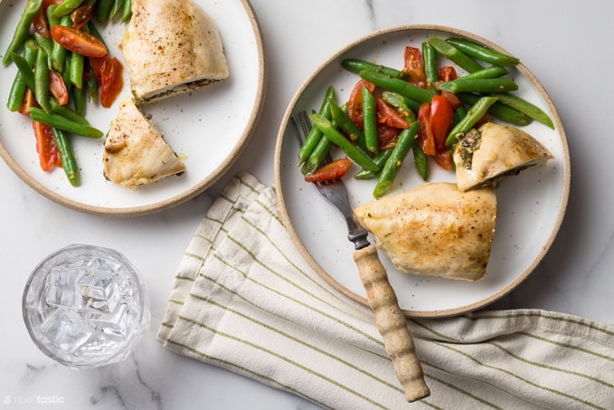 Pesto stuffed chicken on a plate with green beans