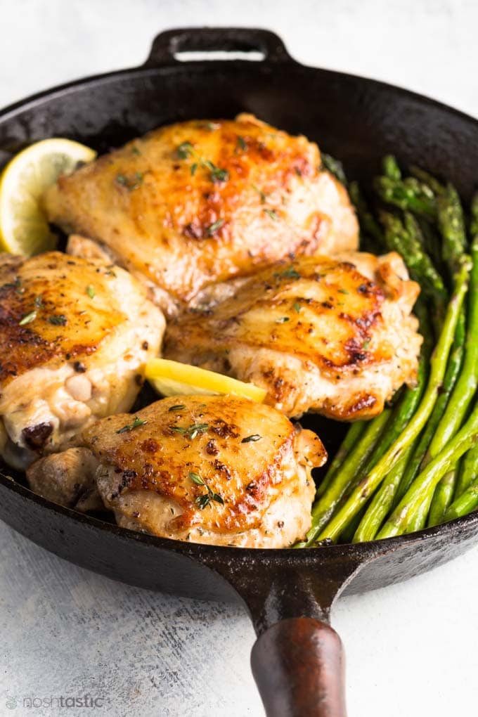 Roasted Lemon Thyme Chicken with asparagus in a cast iron skillet.