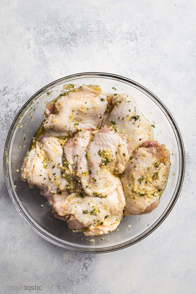 Marinating chicken thighs in bowl with lemon and garlic