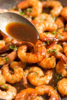 spooning honey garlic sauce over cooked shrimp
