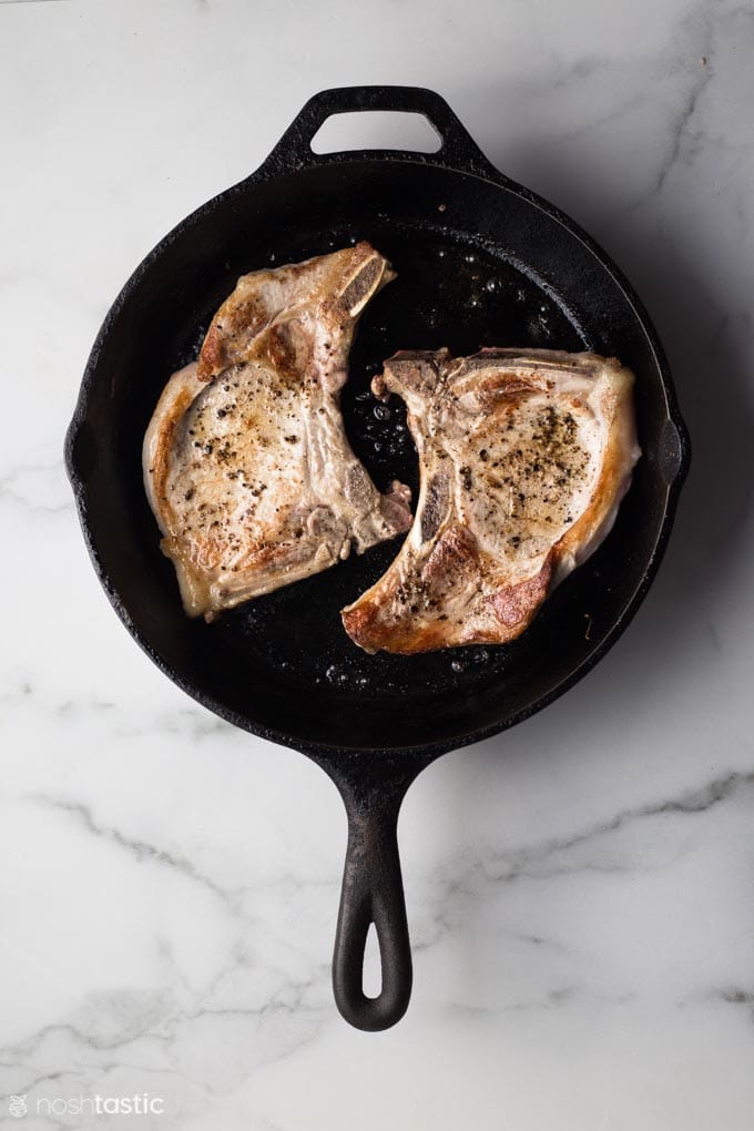 browned pork chops in a cast iron skillet