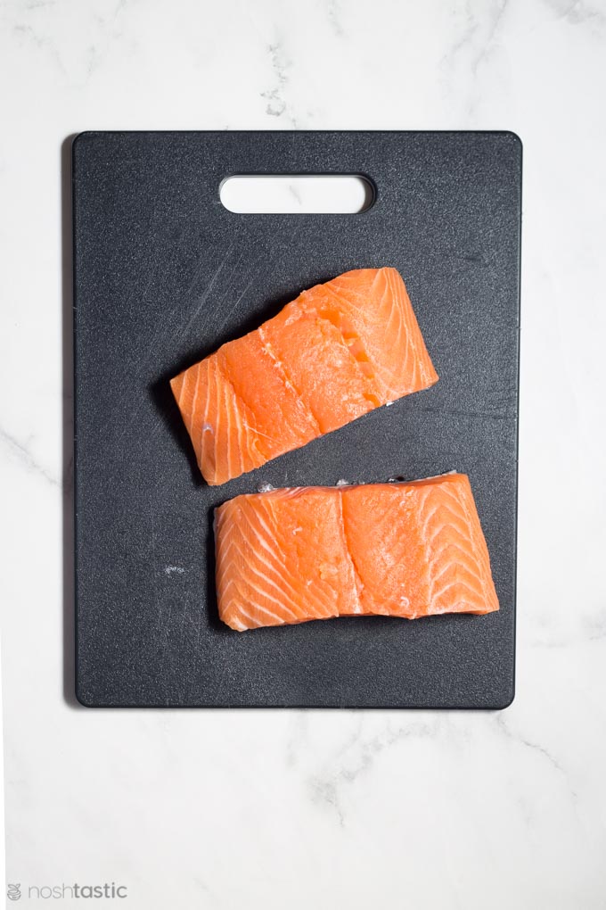 Two salmon fillets on a cutting board