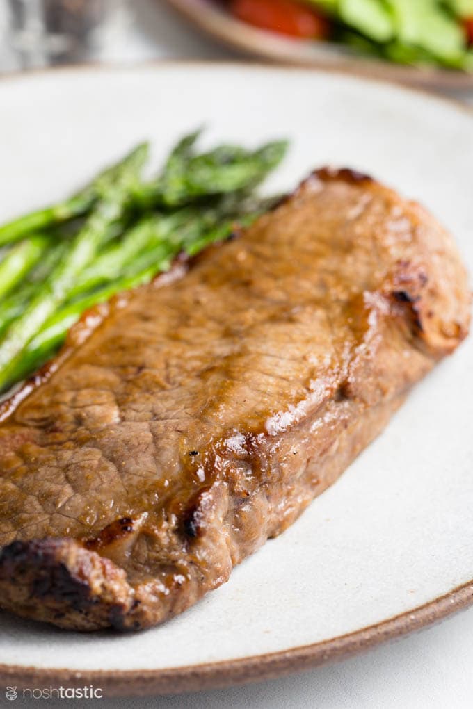 cooked strip steak on a plate with asparagus