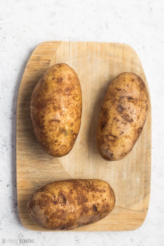 Washed Russet potatoes on a wood board