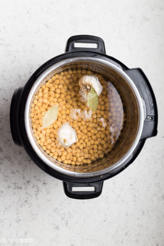 uncooked chick peas, bay leaves and garlic in a pressure cooker