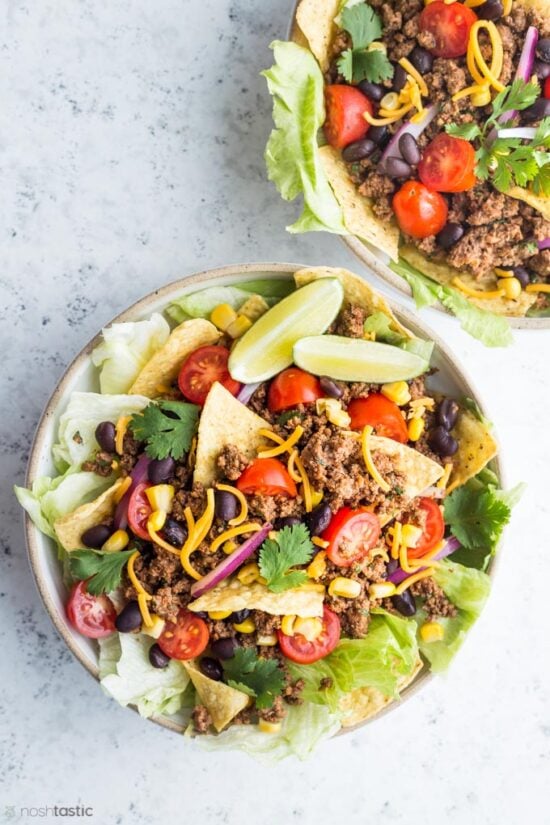 Taco salad with tomatoes cheese and slice of lime in two bowls