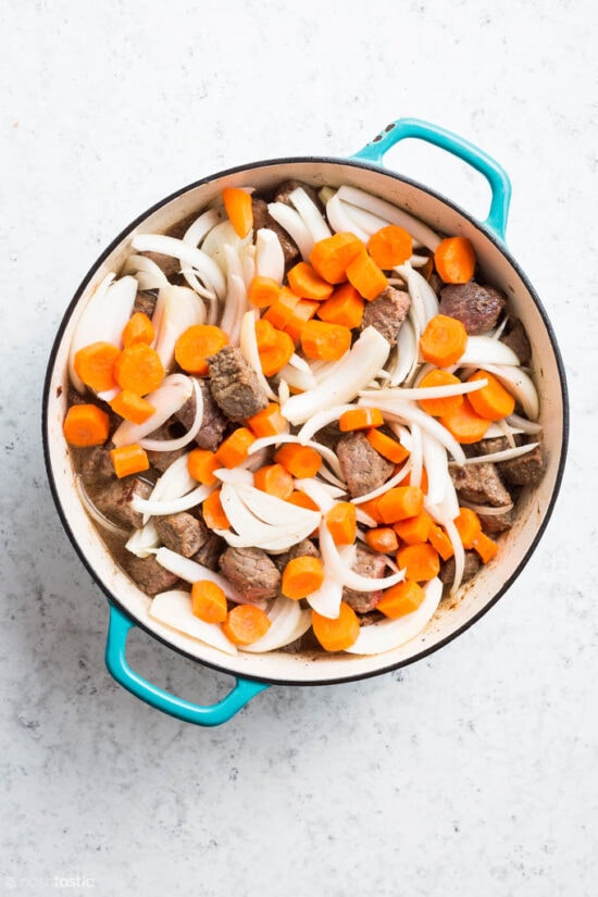 browned beef, onions and carrots in a Dutch oven