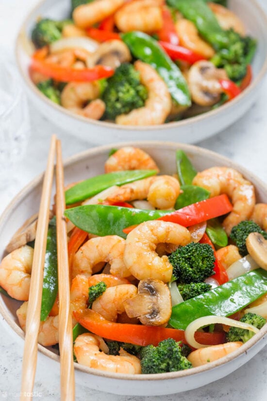 shrimp broccoli snow peas stir fry in bowl with chopsticks