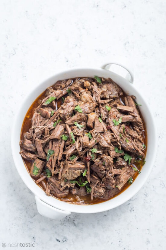 Barbacoa in a white dish with cilantro garnish