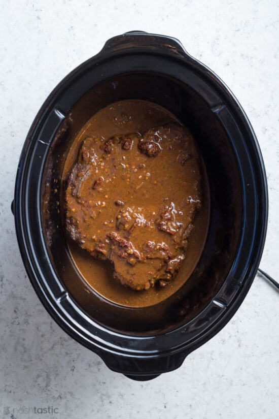 chuck roast covered with Adobo sauce in a slow cooker